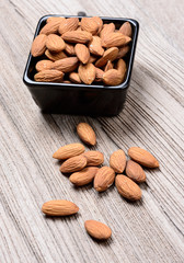 almonds with ceramic bowl on grained wood background