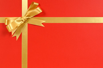 Gold gift bow and ribbon border frame for christmas or birthday present on a red wrapping paper background photo