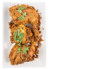 Popular Javanese dish Ayam Penyet or crispy fried chicken in a white plate over wooden background