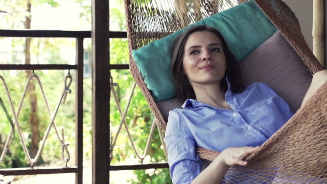 Happy woman relaxing on hammock on terrace 
