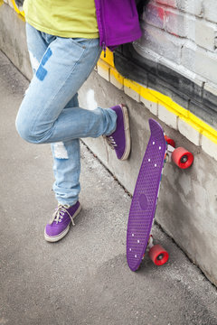 Teenager in jeans stands with skateboard