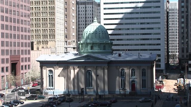 A charming domed building is dwarfed by the surrounding skyscrapers in this downtown shot.
