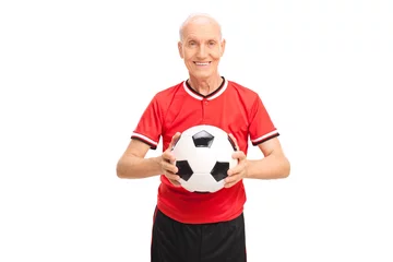 Rolgordijnen Senior man in a red jersey holding a football © Ljupco Smokovski