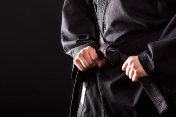 Close-up van mannelijke karatevechter die de knoop aan zijn zwarte band bindt