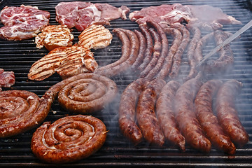 Sausages and pork fried meat, placed on the grill.