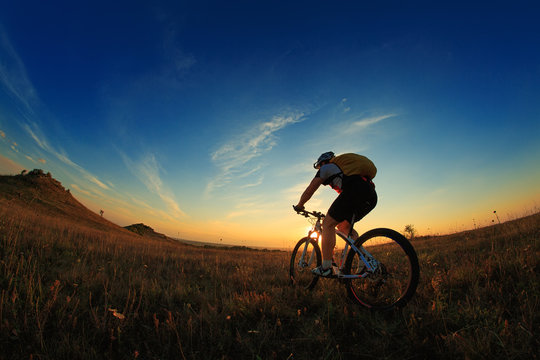 Silhouette of a biker and bicycle on sky background.