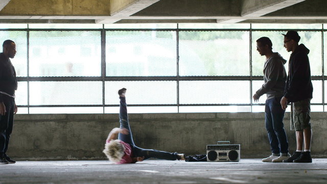 4K Flexible female breakdancer takes to the floor and shows her moves as friends cheer her on, in slow motion, shot on Red Epic Dragon