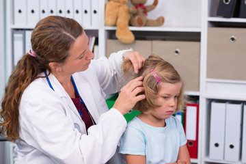 female pediatrician in white lab coat examined little patient