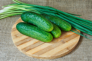 Fresh cucumbers and green onions on a wooden tray