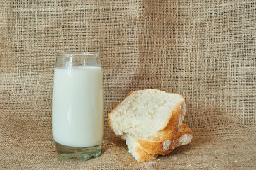 A glass of milk with bread on a burlap in a rustic style.