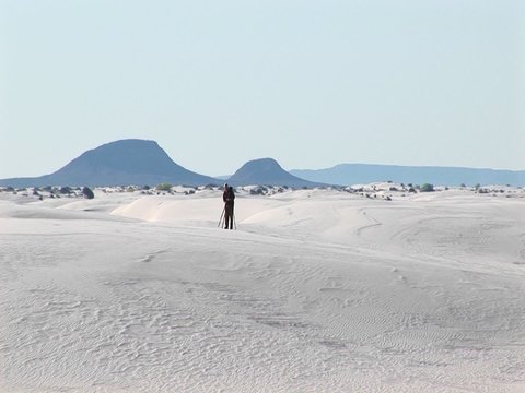 Long-shot of a photographer setting up a tripod in White Sands National Monument in New Mexico.