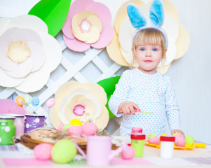 Pretty little girl painting eggs