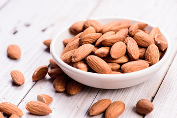 almonds - a ceramic bowl on grained wood background