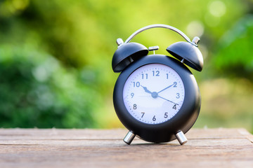 green bokeh background with retro alarm clock on wood table