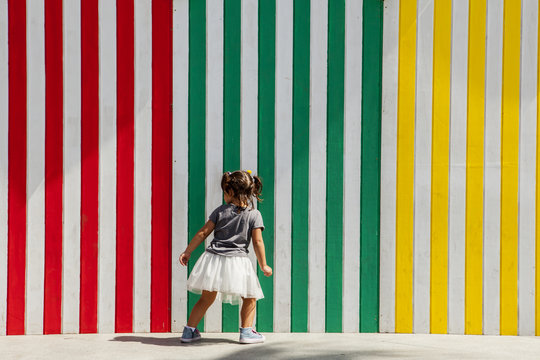 Playing beside striped colored wall