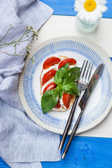 Toast with cherry tomato, mozzarella and basil leaves