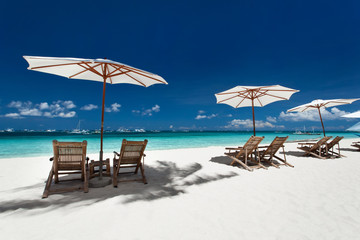 Sun umbrellas and wooden beds on tropical beach