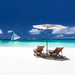 Sun umbrellas and wooden beds on tropical beach