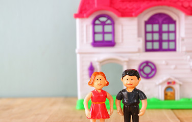 concept image of young couple in front of new house. little plastic toy dolls (male and female) , selective focus.

