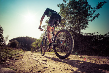 Man riding on a dirty road on a mountain bike - obrazy, fototapety, plakaty