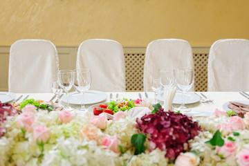 Beautifully served table in a restaurant / Beautiful holiday table setting in white color with flower composition on the table