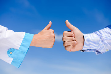 Thumb up between doctors over blue sky sunny outdoors background
