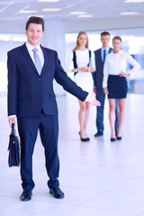 Portrait of young businessman in office with colleagues in the