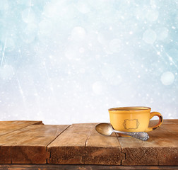 front image of coffee cup over wooden table in front of glitter background with glitter overlay
