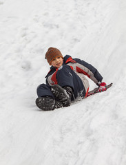 Winter fun - sledding at winter time. Young boy enjoying a sledge ride in a snowy winter park.