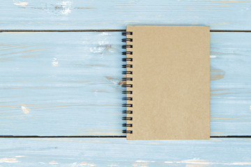Brown notebook on wooden background.