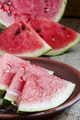 Watermelon slices with ice on a clay plate, selective focus
