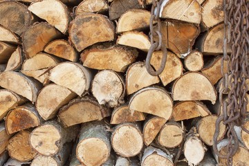 Fototapeta premium Background of stacked wood. Ready firewood. Various kinds of wooden logs stacked on top of each other. Stack of wood, firewood, background. Dry chopped firewood logs ready for winter. 