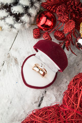 Wedding ring among Christmas decorations on wood background.