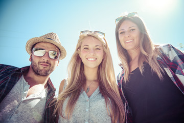 Three students standing over blue sky. Lower point of view
