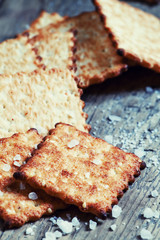 Salty cracker and sea salt on a dark wooden background, toned im