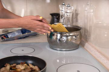Woman placing spaghetti into a pot