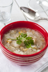 Fish soup in a red striped bowl on a table in an open air restaurant