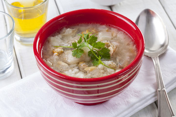Fish soup in a red striped bowl on a table in an open air restaurant