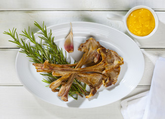 Grilled lamb chops with garlic sauce on a white wooden table