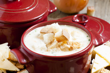 Cheese soup with croutons in red portioned saucepan, selective f