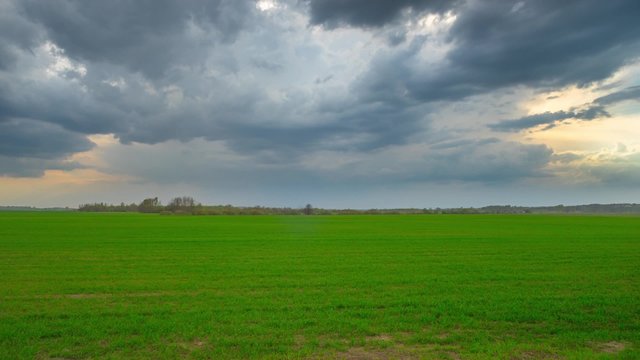 green field and storm clouds, panoramic time-lapse