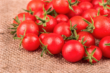 Pile of fresh small red cherry tomatoes close-up on sacking