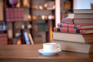 Stack of old books and cup with coffee over wooden table, retro filtered image