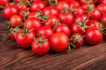 Scattered small fresh cherry tomatoes on a wooden background