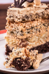 Piece of cake with chocolate and cream in a spoon on a plate close-up