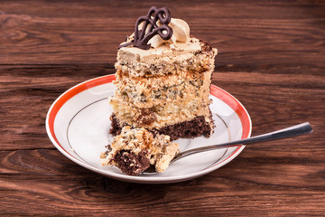 Piece of cake with chocolate and cream in a bowl on a wooden table