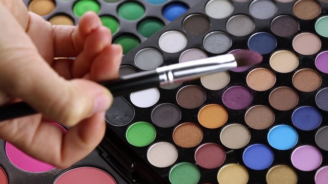 Make-up artist taking eye shadows from makeup eyeshadows palette
