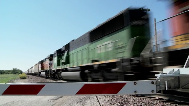 A freight train speeds past a gated railroad crossing.