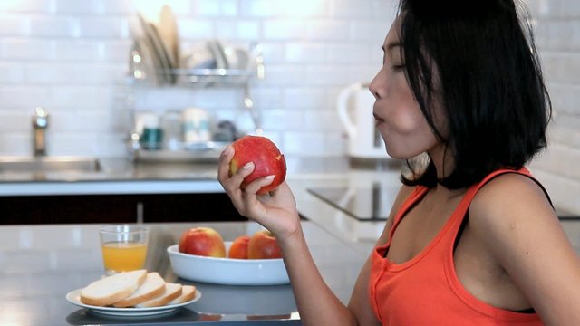 woman in the kitchen eating red apple