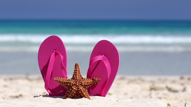 Pink flip flops, swimming glasses and starfish on white sandy beach. Summer vacation conceptPink flip flops and starfish on white sandy beach. Summer vacation concept

